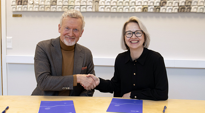 Mann og kvinne som håndhilder og ser smilende i kamera