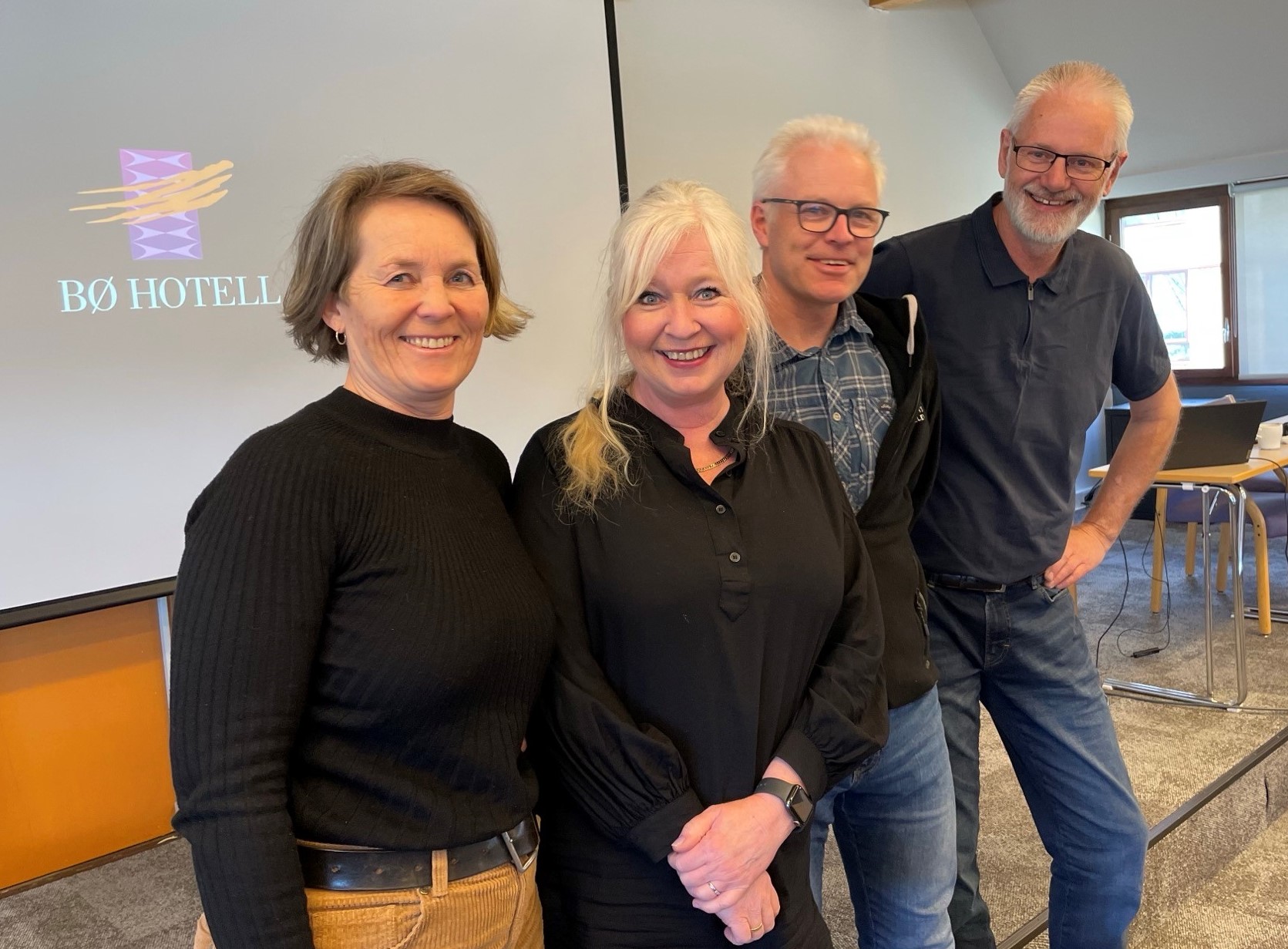 To damer og to menn smiler mot kamera