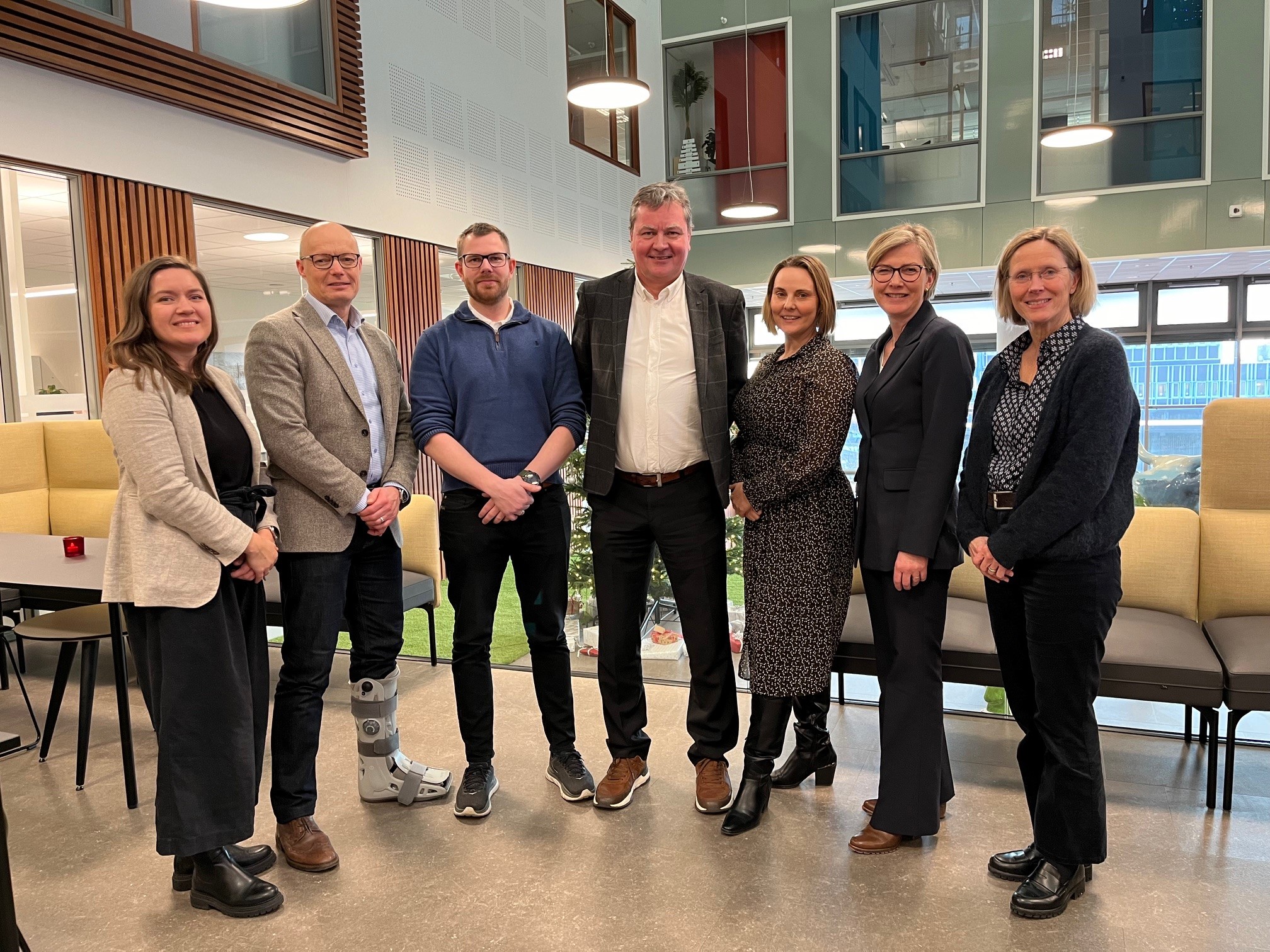 Syv mennesker står ved siden av hverandre og smiler til kamera