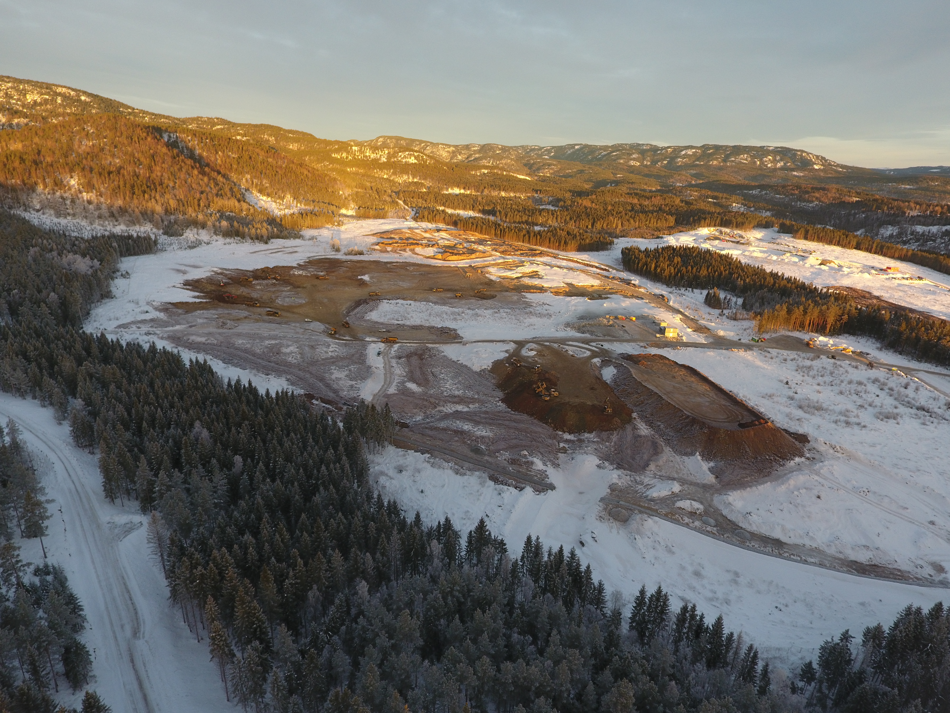 Byggeområde med hauger med jord, omgitt av skog