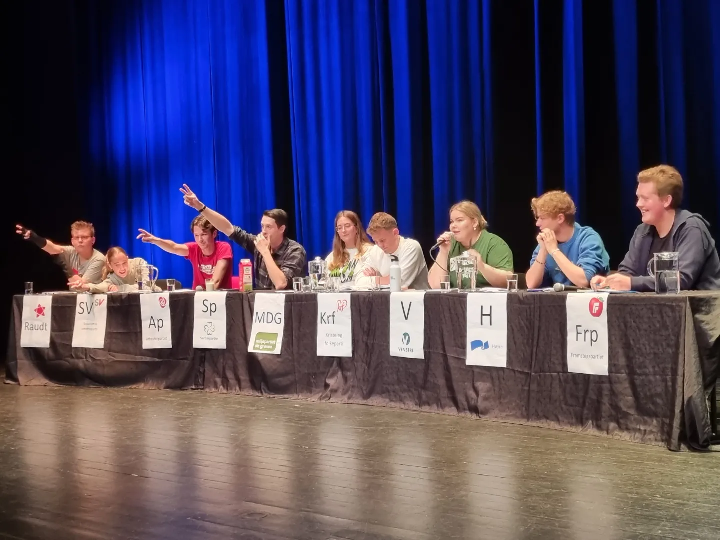 Ungdommer fra ulike partier som sitter ved et langt bord og debatterer.