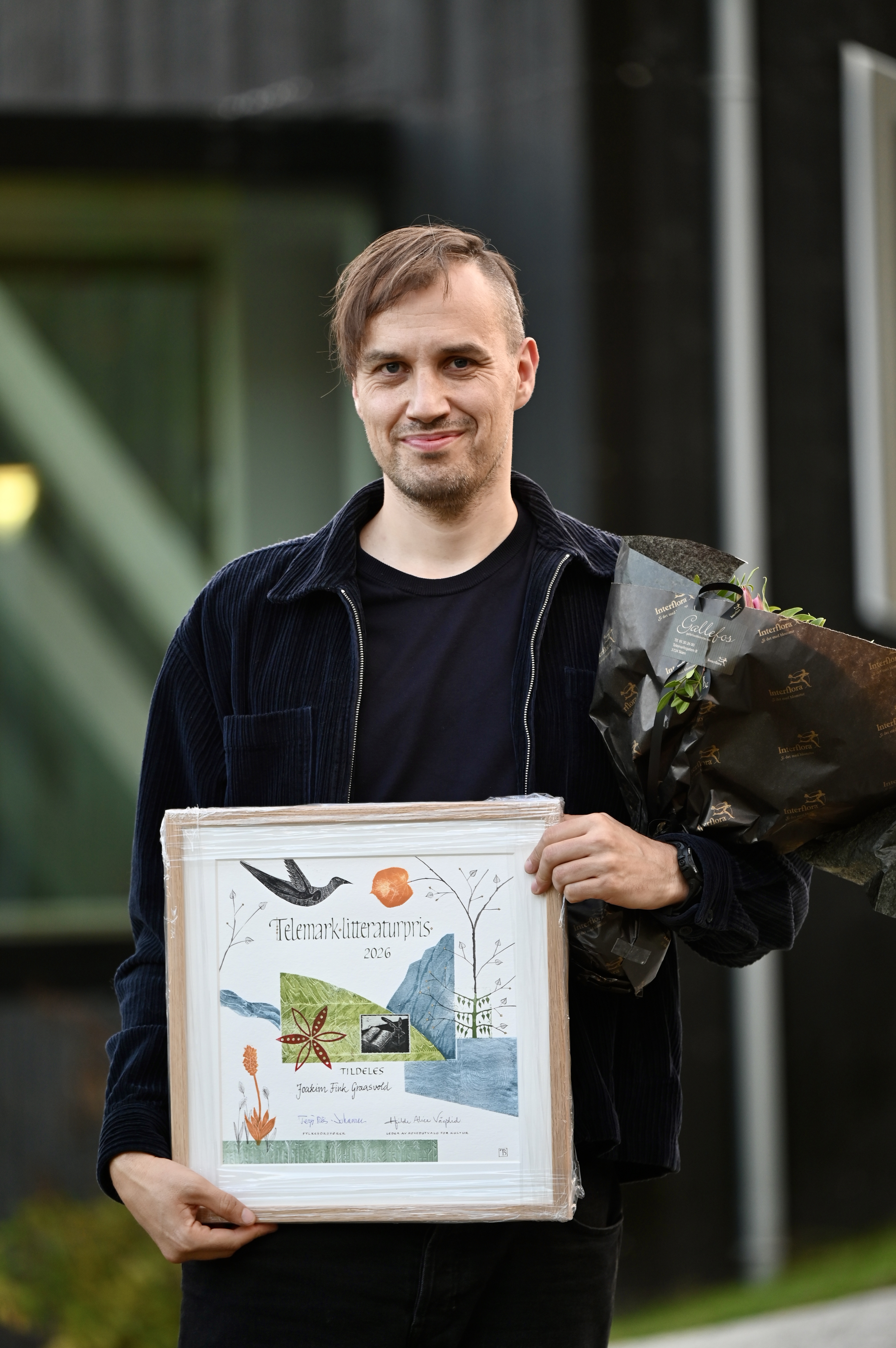 En mann holder et diplom for Telemark litteraturpris.