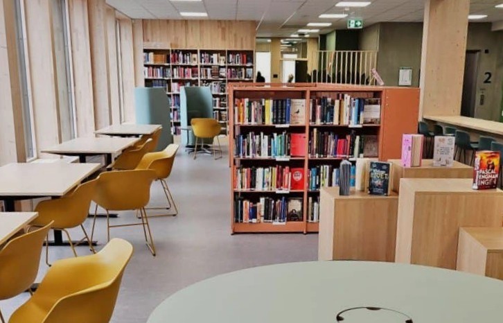 Bildet viser et bibliotek, med bokhyller og sitteplasser.