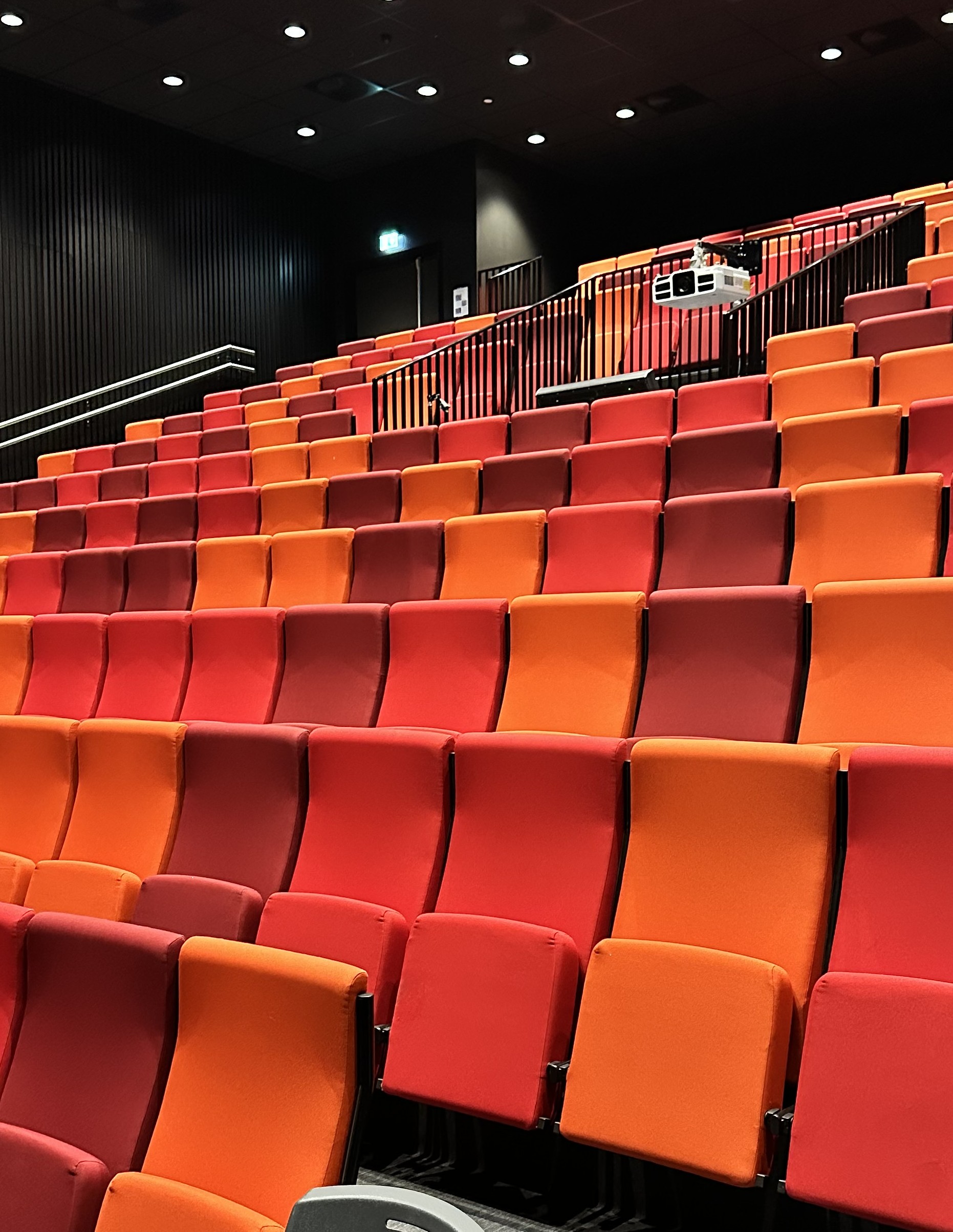 Tomme rader med røde stoler i et auditorium