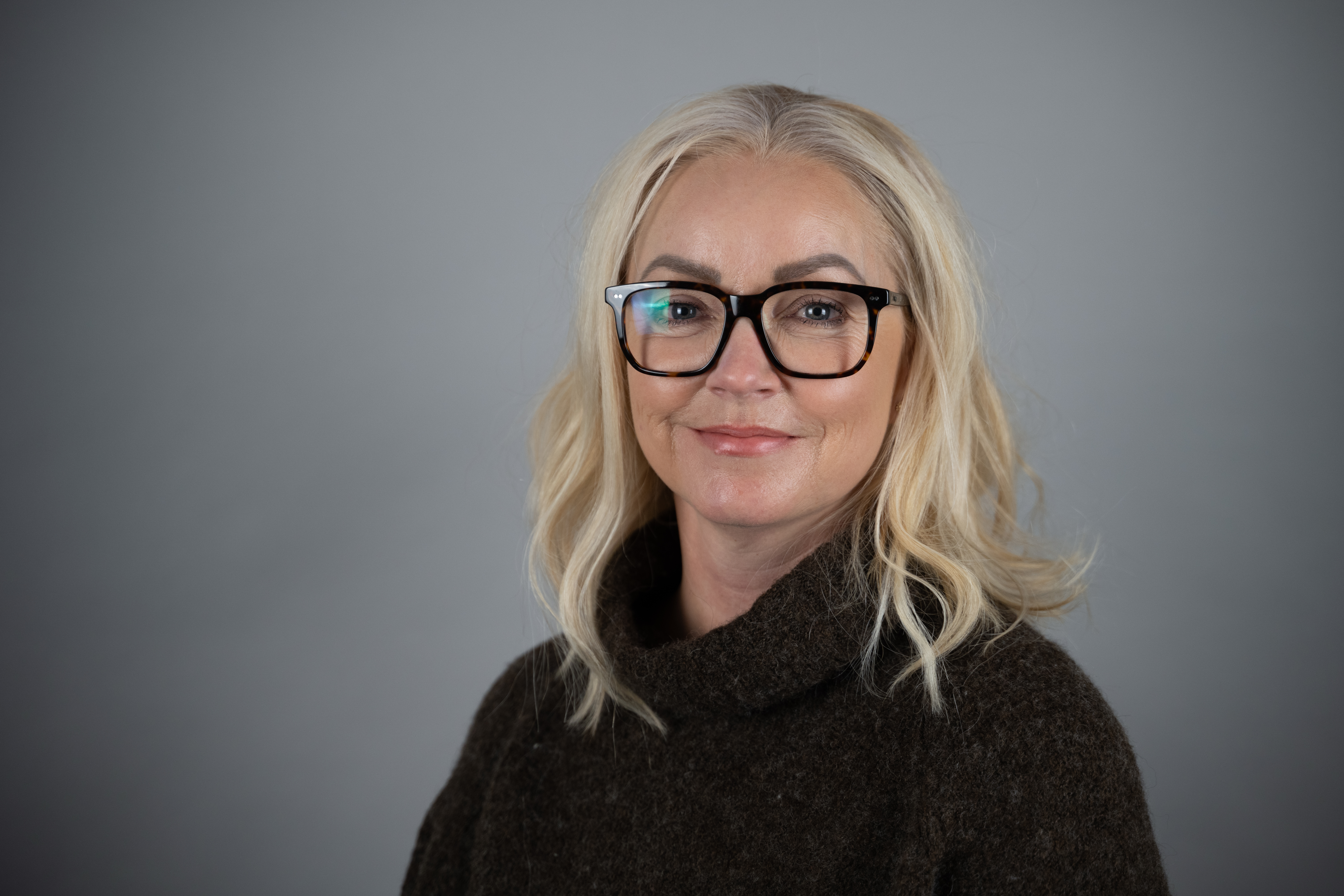 Bilde av kvinne med lyst hår og briller med svart innfatning.