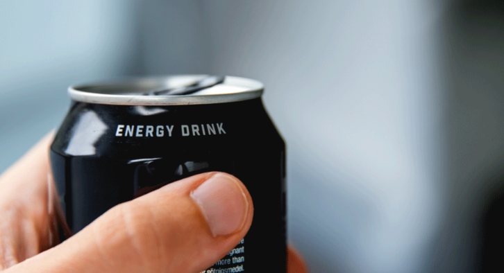 En hånd som holder en boks med drikke som det står teksten "Energy Drink" på