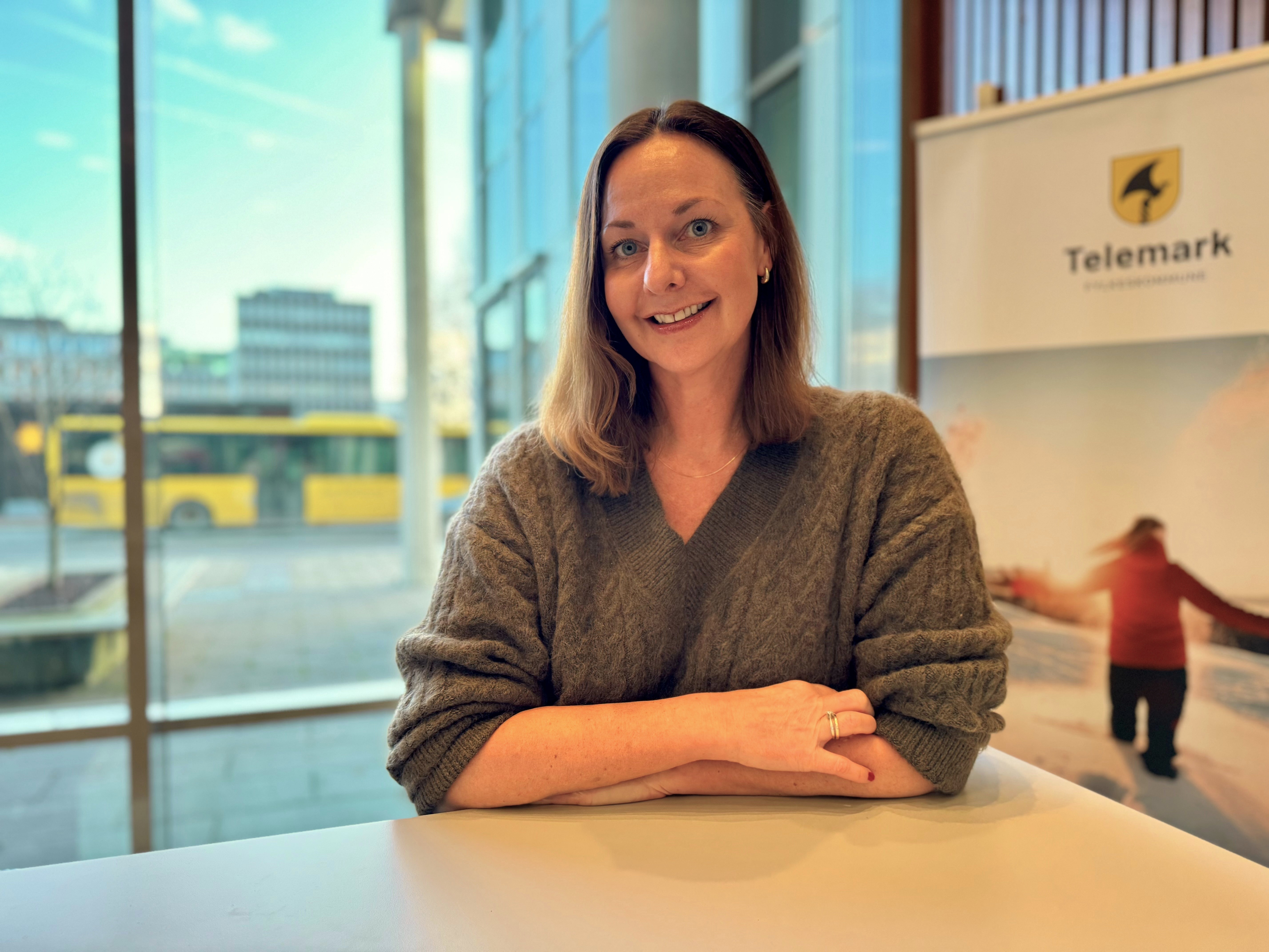 Kvinne i strikkegenser som ser i kamera og smiler