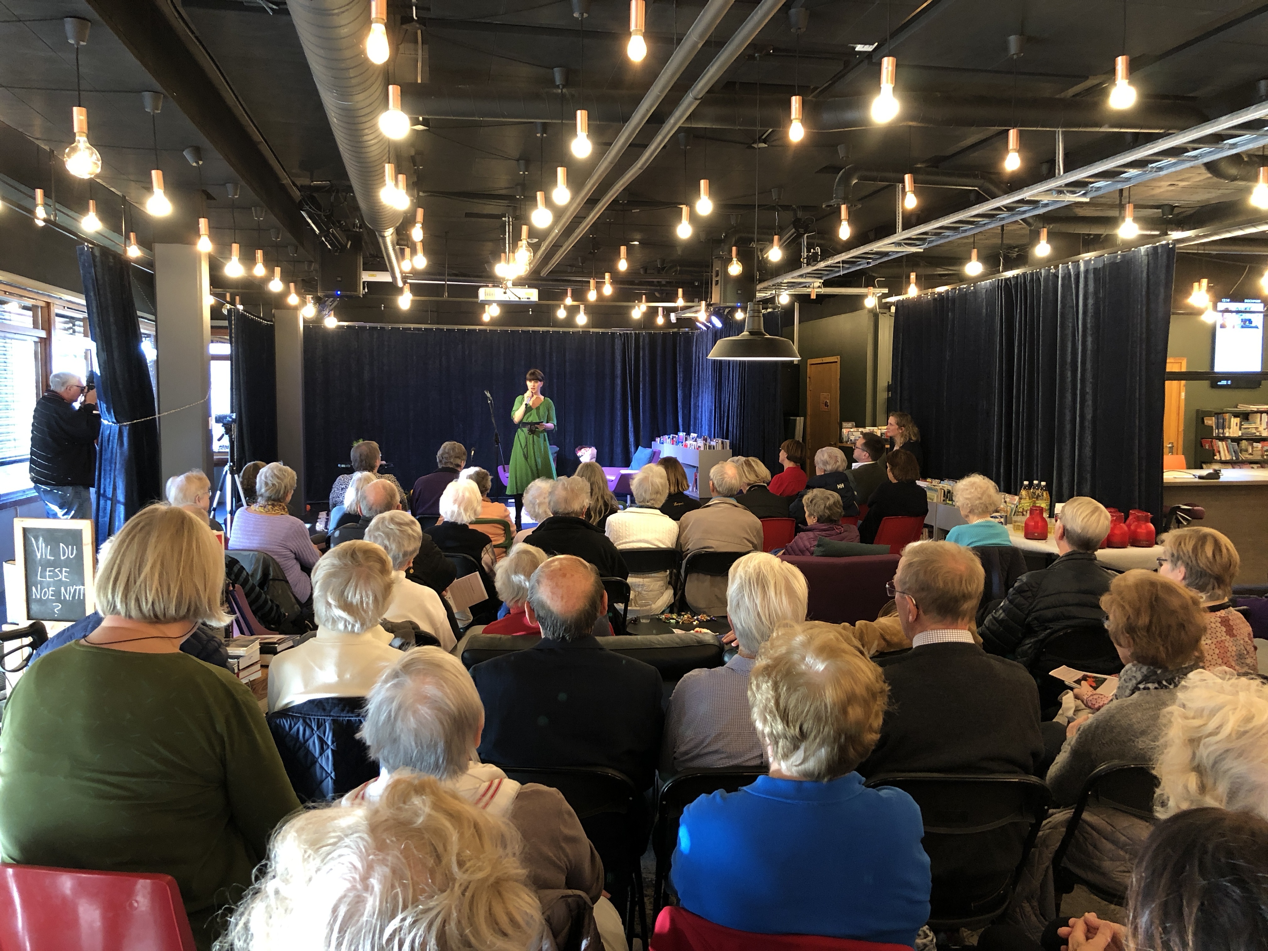 En folkemengde som ser på en scene i biblioteket